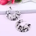 Detailed view of C-shape clear acrylic earrings with black and white stone confetti inside. - Color 6