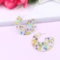 Close-up detail of C-shaped transparent acrylic earrings filled with colorful gemstone glitter. - Color 7