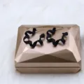 Close-up detail of stylish black geometric spiral earrings, showcasing unique matte textured design. - Telephone Cord Style