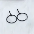 Close-up detail shot of minimalist black geometric drop earrings, modern style. - Round Row
