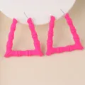 Nahaufnahme von leuchtend rosa dreieckigen Bambus-Ohrringen, modischem Acryl-Schmuck. - Fuchsia