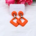 Pendientes colgantes geométricos de acrílico naranja brillante en tarjeta de exhibición. - Naranja