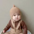 Vue detaillee du bonnet bebe en tricot avec joli noeud pour l'hiver et brides chaudes. - Kaki