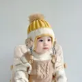 Vista detallada del tierno gorro de invierno tejido para bebé con pompón y orejeras. - 6-48 Meses 44-50cm / Amarillo
