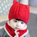 Primer plano detallado de un bonito gorro de punto rojo para bebé con una bufanda gruesa. - Rojo