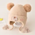 Cute baby knit hat with double pom poms and cute bear embroidery for winter warmth and cozy wear. - One Size / Beige