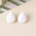 Close-up detail shot of minimalist white teardrop acrylic stud earrings, smooth texture. - White