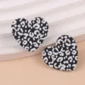 Detailed close-up shot of black and white leopard print heart acrylic earrings fashion jewelry. - Black Leopard