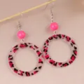 Close-up detail shot of vintage leopard print acrylic hoop earrings featuring bright pink beads. - Rose Red