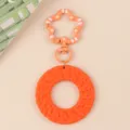 Orange acrylic round keychain pendant with braided texture, simple bohemian style fashion accessory detail shot. - Orange