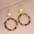 Close-up detail of vintage leopard print acrylic hoop earrings with bright yellow bead accent. - Yellow Leopard