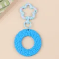 Detailed view of a candy color round acrylic keychain with a cute flower clasp accessory. - Blue