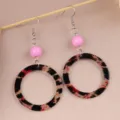 Close-up of retro leopard print acrylic circle earrings with pink beads and metal hooks. - Red & Black