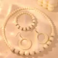 Close up detail of cream bead necklace bracelet and hollow round pendant earrings jewelry set. - White Zirconia Set