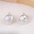 Gros plan détaillé des boucles d'oreilles clous sphériques en métal argenté à texture martelée. - Rond / Argent