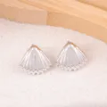 Close-up view of silver shell stud earrings, featuring detailed textured design for daily wear. - Shell / Silver