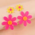 Gros plan détaillé de boucles d'oreilles tournesol en acrylique fluorescent coloré, bijoux originaux. - Rose rouge