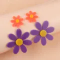 Detailed close-up of vibrant acrylic sunflower drop earrings in purple and orange colorway. - Purple
