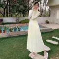 Outdoor scene detail of a lightweight long hooded yellow sun protection dress in garden. - M / Yellow