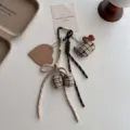 Gedetailleerde close-up van schattige pluche kat ruit sleutelhanger en hartvormige hanger. - Licht Khaki Strik Stijl