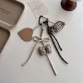 Gedetailleerd close-up van de schattige pluche kat sleutelhanger met geruite strik. - Licht Khaki Oorwarmers Stijl