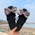 Detailaufnahme von Damen Strand-Flip-Flops mit großen glänzenden Pailletten-Schleifen auf der Sohle. - M (EU 38-39) / Schwarze Sohle