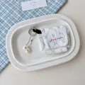 Mini stoffen oortelefoon opbergtas met schattig strikmotief en sleutelhangerbedel. - Kleine Witte Bloem