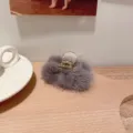 Détail de pince à cheveux en fourrure de vison peluche grise, accessoire élégant sur plateau bois. - S / Gris