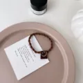 Chouchou tressé marron avec étiquette en tissu smiley mignon et élastique pour femmes. - Tressé Petit Visage Souriant / Marron
