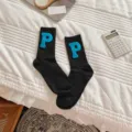Primer plano de calcetines negros de media altura con parches suaves letra P azul. - Talla única / Calcetines Negros + P Azul Lago