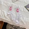 Gros plan de chaussettes blanches avec un patch de lettre C rose, style collégien. - Taille unique / Blanc avec C Rose