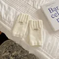 Primo piano dettagliato di comodi guanti lavorati a maglia bianca senza dita e etichetta. - Taglia unica / Bianco