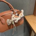 Cute fluffy dachshund plush bag charm with metallic heart pendant and leather braided strap detail. - Milk Tea Spotted Dachshund