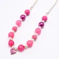 Close-up detail of children beaded necklace with cute glitter heart pendant and beads. - Rose Red