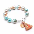 Vue detaillee du bracelet de perles colorees pour enfants avec coquillage et pompons. - 7