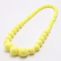 Close-up detail of the yellow acrylic bead children necklace, showing smooth glossy bead surface. - Yellow