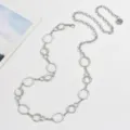 Silver metal chain belt detailed with interlocking oval rings and a delicate charm accessory. - Loop Waist Chain / Silver