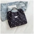 Floral crinkle tote bag detail showing dark fabric with pink flower print and shoulder straps. - Black