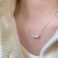 Gros plan détaillé d'un collier en chaîne argentée fine avec pendentif en perles dégradées. - Argent 925 / Or blanc