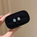 Gros plan de boucles d'oreilles clous ovales en zircon bleu élégantes avec des diamants étincelants. - Avec Fermoirs en Plastique / Boucles d'Oreilles Clous Zirconia Bleu Ovale - Couleur Or Blanc