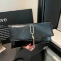 Detailed view of black PU leather envelope clutch bag with golden ring and elegant tassel decor. - Black
