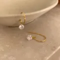 Gros plan de boucles d'oreilles pendantes minimalistes en argent doré avec cristal étincelant. - Argent 925 / Ton Or