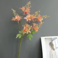 Detailed view of artificial peach blossom branch with realistic pink flowers and green leaves. - Champagne Orange