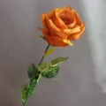 Vista de detalle en primer plano de una rosa artificial naranja con tallo y hojas verdes. - Café y Amarillo