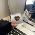 Mini silberne Kussverschluss Umhängetasche mit Leo-Herz Detail und Kette, trendig. - Herz / Silber