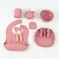 Silicone baby feeding set detail view, pink bib, divided plate, bowl, cup, and wooden spoon. - Dark Pink 10-Piece Round Plate Set