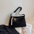 Black suede underarm shoulder bag with chic wooden bead charm, stylish and minimalist design. - Black