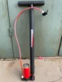 Detail view of a portable multi-purpose steel floor air pump with pressure gauge and red hose. - One Size / As Shown