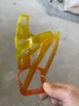 Detailed view of a bright yellow orange transparent plastic bicycle water bottle cage frame. - Yellow