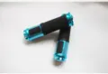 Detailed view of the bicycle handlebar grips featuring blue aluminum and black rubber texture. - One Size / Blue